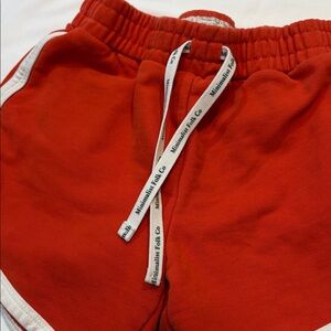 Red "Minimalist Folk Co" Logo Drawstring Dolphin Style White Trim Shorts, 14Y